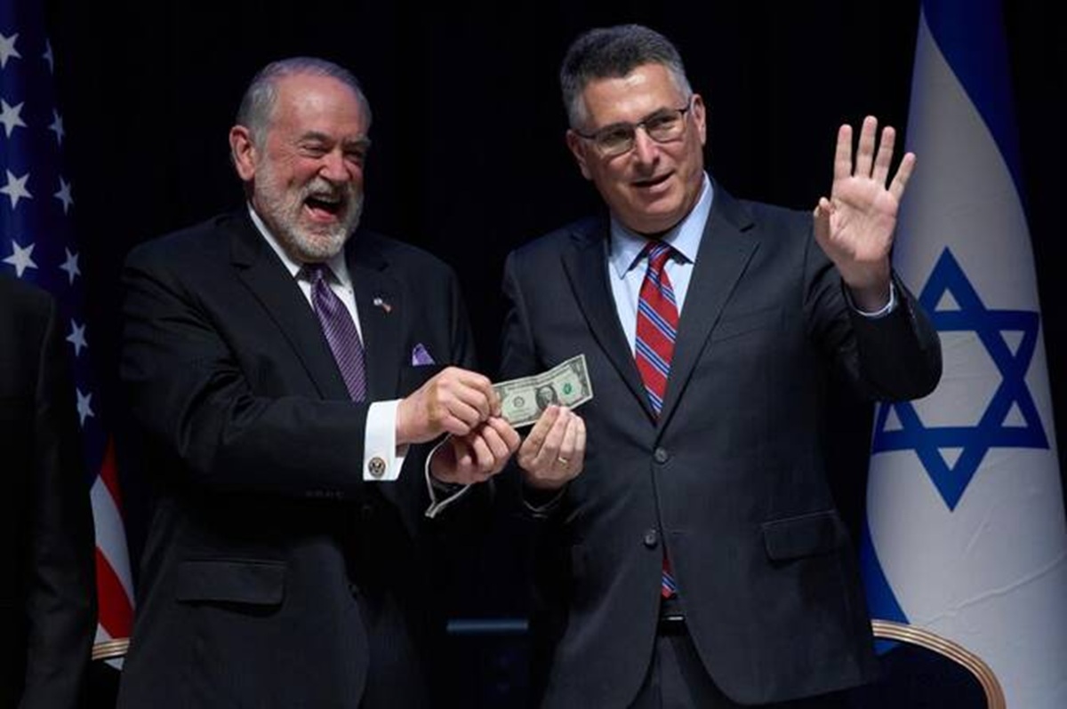 Israeli Foreign Minister Gideon Sa'ar (right) and US Ambassador Mike Huckabee hold up a symbolic one dollar bill, the price of leasing the land for the new embassy, during a ceremony in Jerusalem on Wednesday.