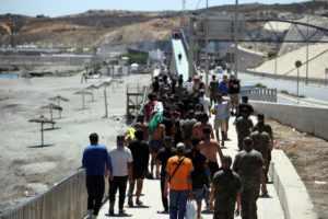 A group of migrants approach the border post to make their way back to Morocco, escorted by Spanish infantry soldiers, in the Spain's north African enclave of Ceuta, on August 2, 2026.