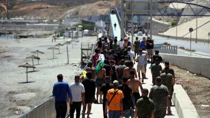 A group of migrants approach the border post to make their way back to Morocco, escorted by Spanish infantry soldiers, in the Spain's north African enclave of Ceuta, on August 2, 2026.