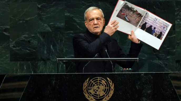 Iranian President Masoud Pezeshkian holds up pictures of alleged victims killed during the Israeli and American air strikes