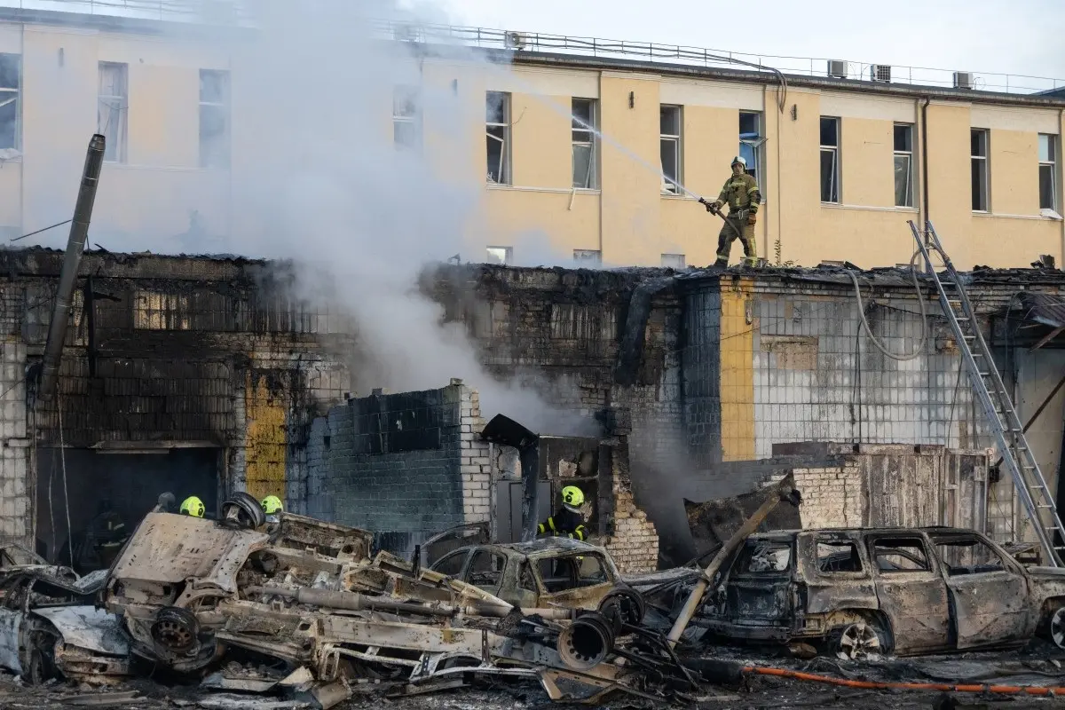 Smoke rises from a building near wrecked cars as firefighters battle a blaze following Russian missile strikes amid Russia's invasion of Ukraine, in Kyiv early on September 8, 2026.