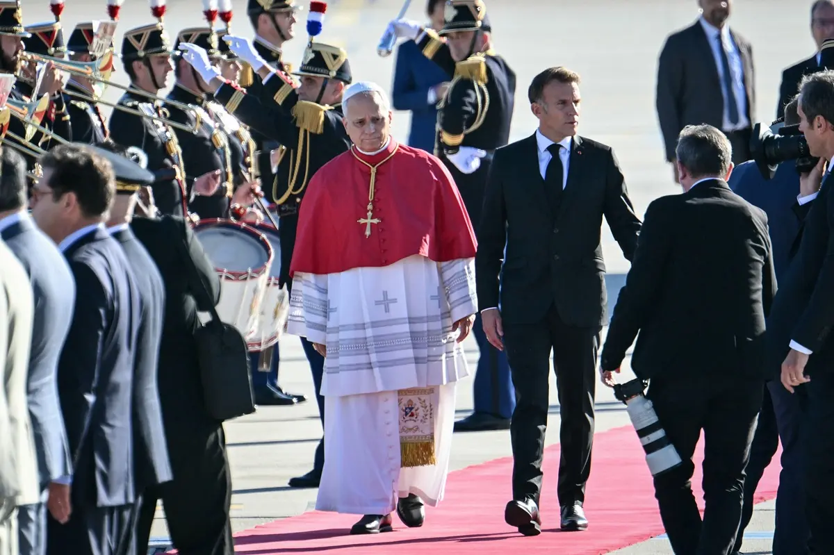 Pope Leo XIV (L) is welcomed by France's President Emmanuel Macron (R) on the tarmac after disembarking from the plane upon his arrival at the Orly airport, in the outskirts of Paris, on September 25, 2026 for his four days visit to France.