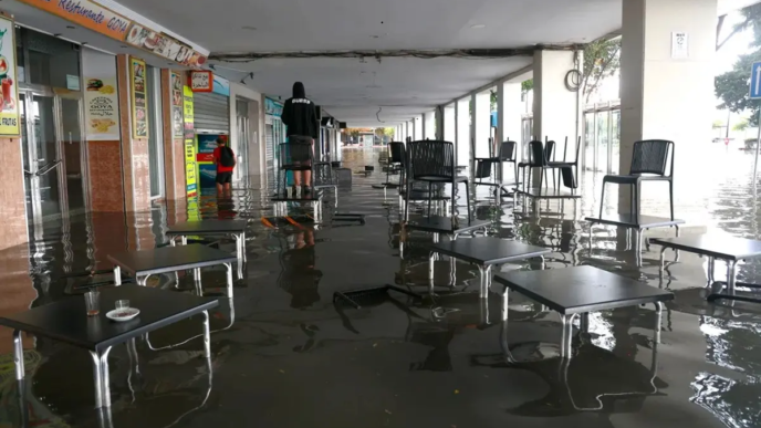 A resident stands on a bar table at a flooded street after heavy rainfall that hit the area early in the morning, in the town of Algeciras, southern Spain, on Oct 18.