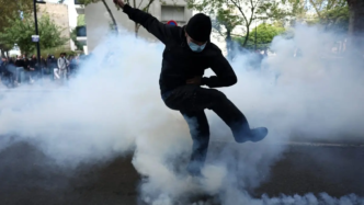 A masked student attempts to kick a tear gas canister, amid clashes with French riot police during a protest by French high school and university students near Lycee Paul Eluard high-school.