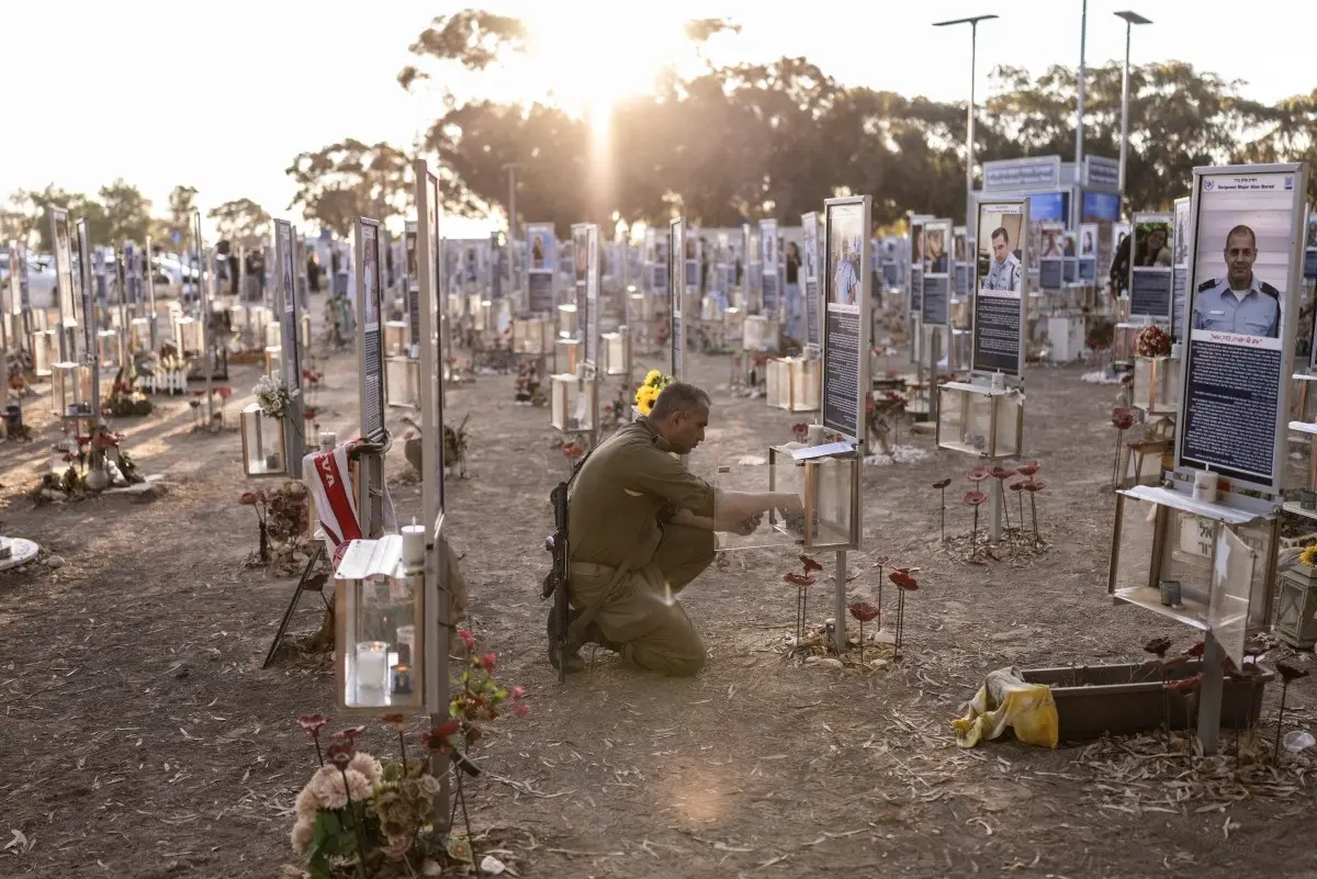 An Israeli soldier crouches to light a candle at the memorial to the victims of the 2023 Hamas attacks at the Nova festival site in Reim, southern Israel, on October 7, 2026. Credit: AFP.