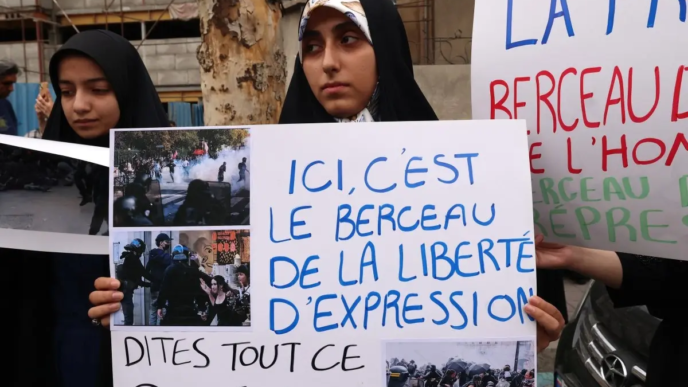 Iranian citizens and students hold signs with images as they gather outside the French Embassy to protest the French police action during nationwide French student protests, in Tehran on October 10, 2026.