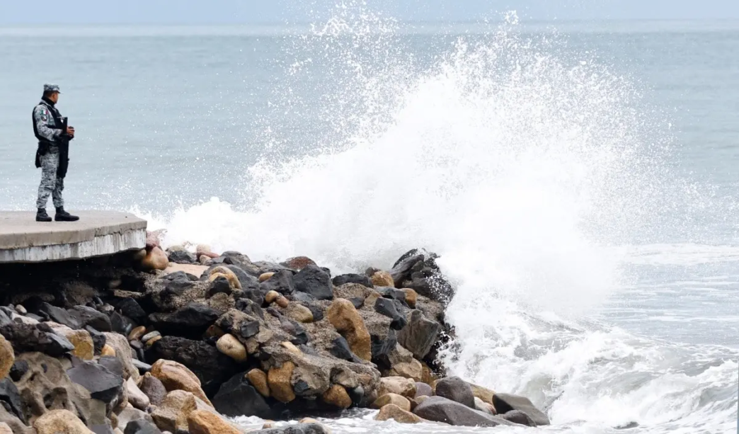 A member of Mexico's National Guard stands on the Puerto Vallarta boardwalk as waves crash against the shoreline ahead of the potential impact of Hurricane Simon in Puerto Vallarta, Jalisco state, Mexico, on October 11, 2026.