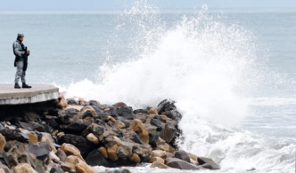 A member of Mexico's National Guard stands on the Puerto Vallarta boardwalk as waves crash against the shoreline ahead of the potential impact of Hurricane Simon in Puerto Vallarta, Jalisco state, Mexico, on October 11, 2026.