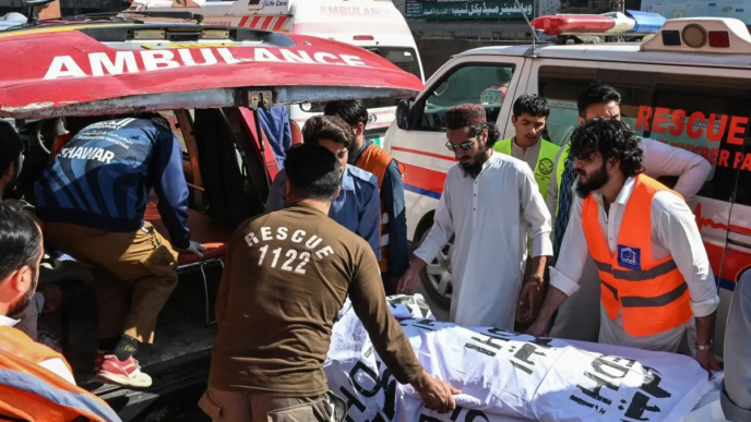 Volunteers and relatives shift the body of a victim, killed after a roof collapsed at a school, into an ambulance outside a hospital in Peshawar on October 15, 2026.