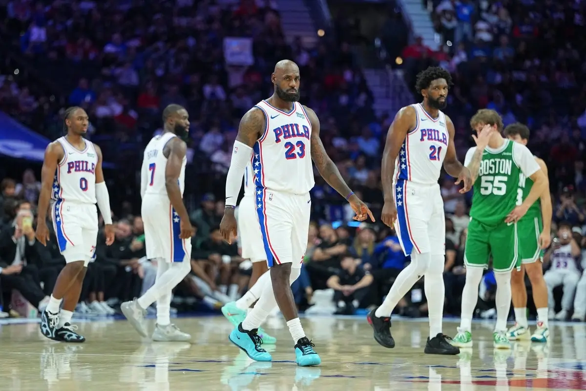 PHILADELPHIA, PENNSYLVANIA - OCTOBER 16: LeBron James #23, Joel Embiid #21, Jaylen Brown #7, and Tyrese Maxey #0 of the Philadelphia 76ers look on against the Boston Celtics in the third quarter during the preseason game at Xfinity Mobile Arena on October 16, 2026 in Philadelphia, Pennsylvania.