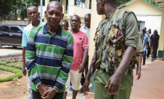 Self-proclaimed pastor Paul Nthenge Mackenzie (L) walks surrounded by Kenya Police Officers and other defendants as he appears at the Shanzu Law Courts in Mombasa on January 18, 2024.