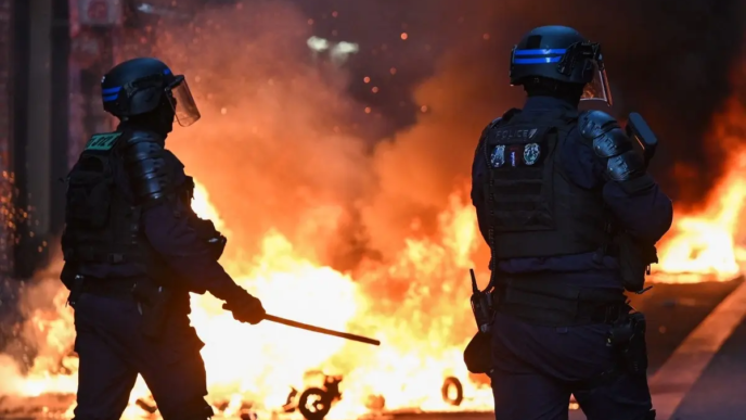 Police officers stand in front of a fire in Faubourg du Temple street as clashes erupted at Place de la Republique following an unauthorised demonstration, central Paris, on October 18, 2026 a day after nationwide protests against the "high cost of living".
