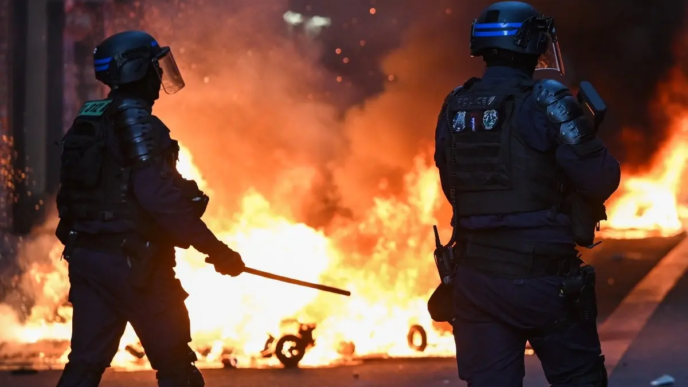Police officers stand in front of a fire in Faubourg du Temple street as clashes erupted at Place de la Republique following an unauthorised demonstration, central Paris, on October 18, 2026 a day after nationwide protests against the "high cost of living".