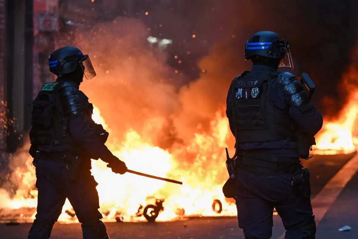Police officers stand in front of a fire in Faubourg du Temple street as clashes erupted at Place de la Republique following an unauthorised demonstration, central Paris, on October 18, 2026 a day after nationwide protests against the "high cost of living".