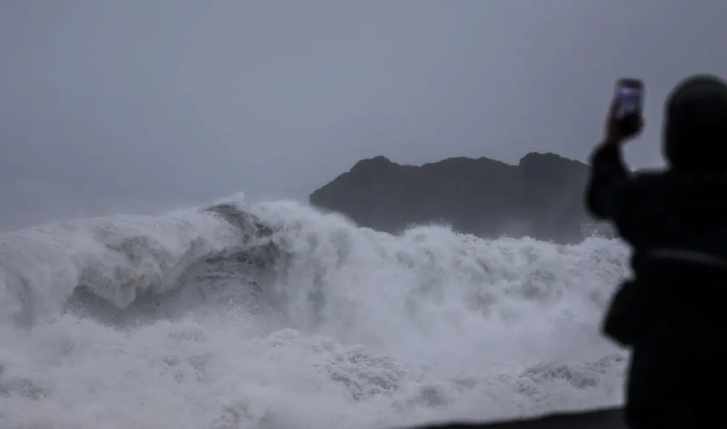 A person takes pictures of waves as Typhoon Champi approaches Taiwan, in Keelung on October 23, 2026.
