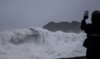A person takes pictures of waves as Typhoon Champi approaches Taiwan, in Keelung on October 23, 2026.