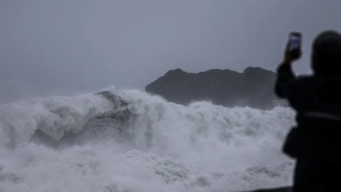 A person takes pictures of waves as Typhoon Champi approaches Taiwan, in Keelung on October 23, 2026.