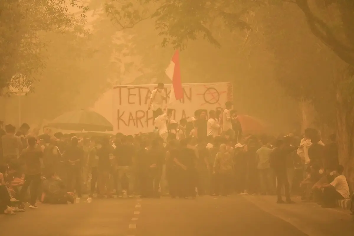 Demonstrators gather amidst heavy haze during a protest demanding action over forest and land fires outside the Central Kalimantan Governor's office in Palangkaraya on October 23, 2026.