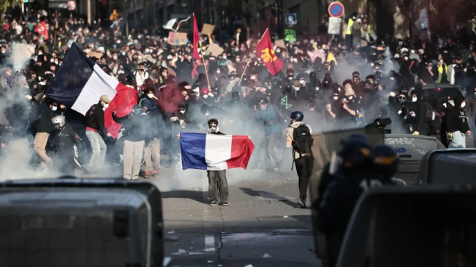 Demonstrators hold French national flags as they confront French Republican Security Corps (CRS - Compagnies Republicaines de Securite) officers during a demonstration in favor of purchasing power, the protection of public services, and fiscal and social justice, in Marseille, southeastern France on October 24, 2026