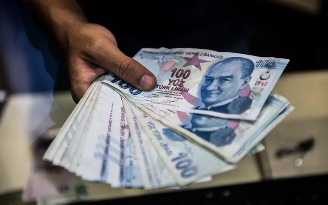 A teller holds Turkish lira banknotes at a currency exchange office in Istanbul on August 13, 2018. 