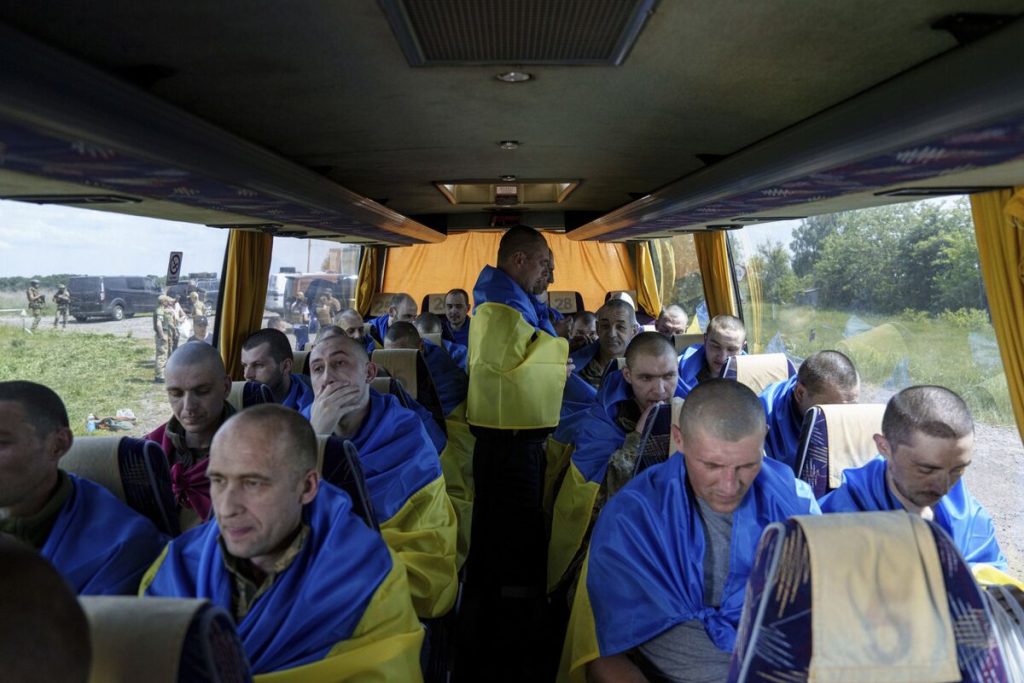 Some Ukrainian prisoners of war holding the national flag after an exchange at an undisclosed location (Handout/Telegram/@Volodymyr Zelensky/AFP)